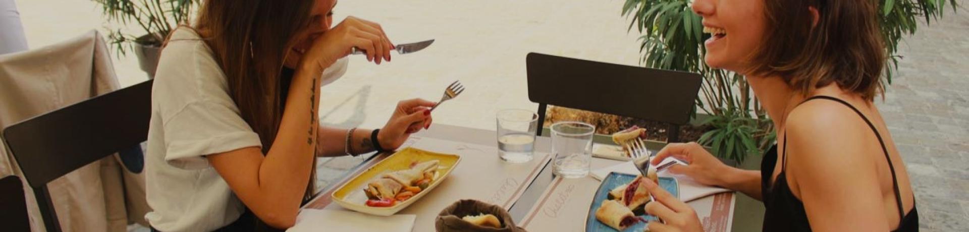 Due amiche ridono mentre pranzano all'aperto in un ristorante.