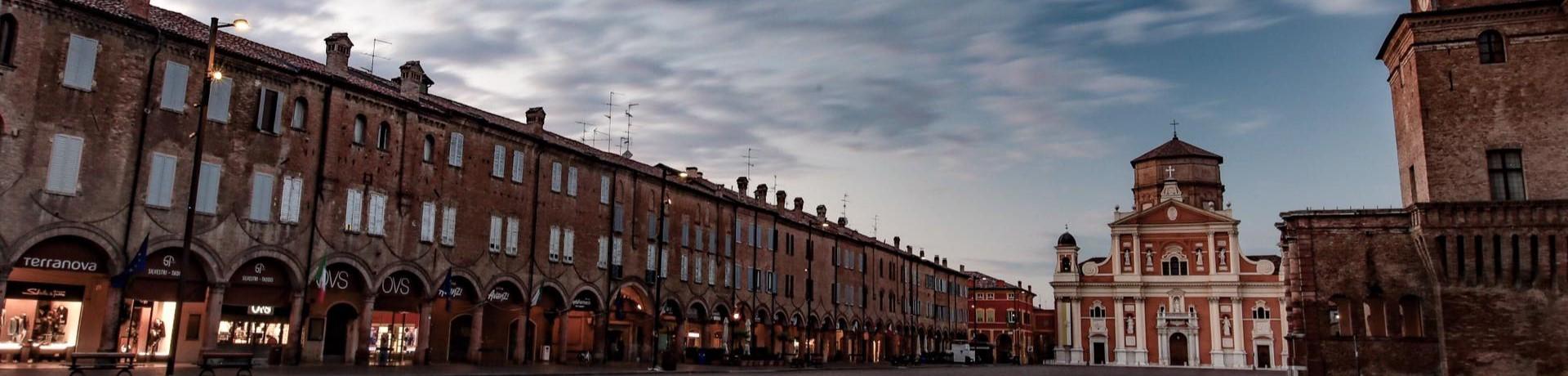 Piazza storica con edifici antichi e una chiesa, sotto un cielo nuvoloso.