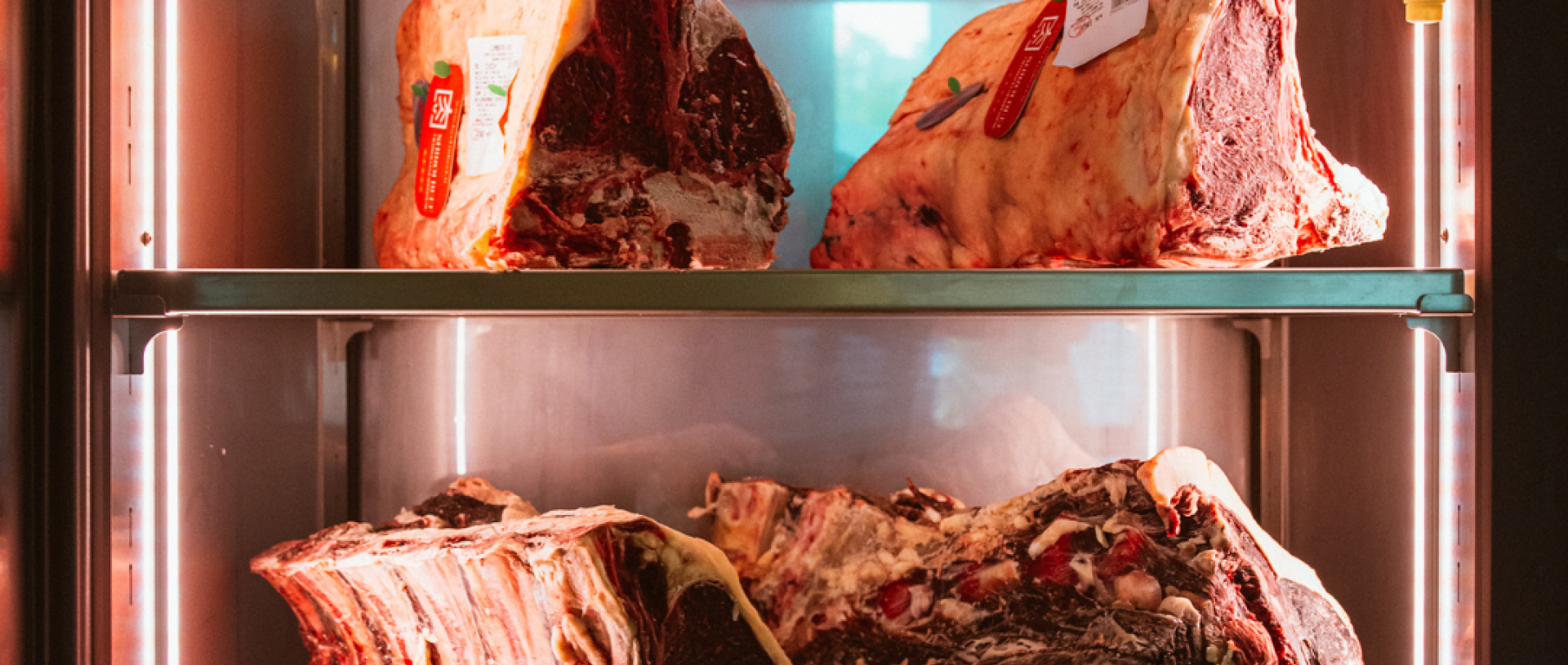 Carni stagionate in esposizione in una vetrina refrigerata di un ristorante.